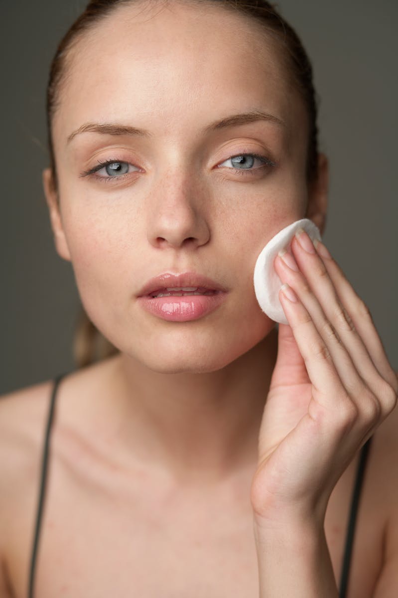 Young woman using a cotton pad for skincare, highlighting beauty routine.