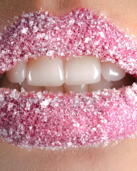 Artistic close-up of lips coated with pink sugar crystals, showcasing beauty and creativity.