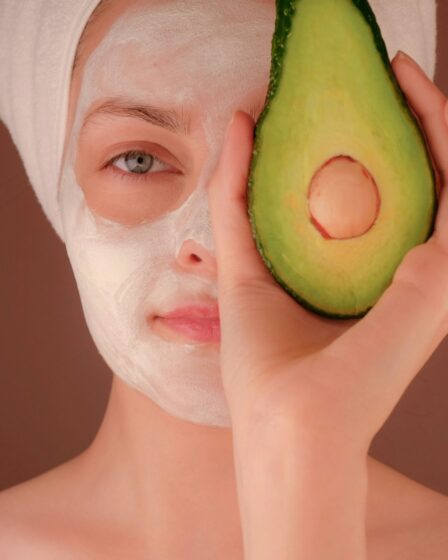 woman with white face mask holding green fruit