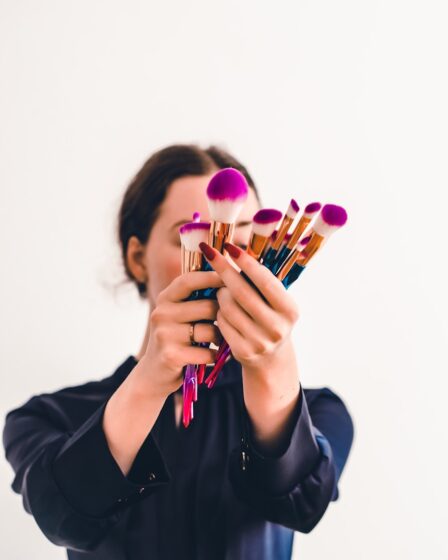 woman in black jacket holding makeup brush