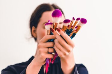 woman in black jacket holding makeup brush